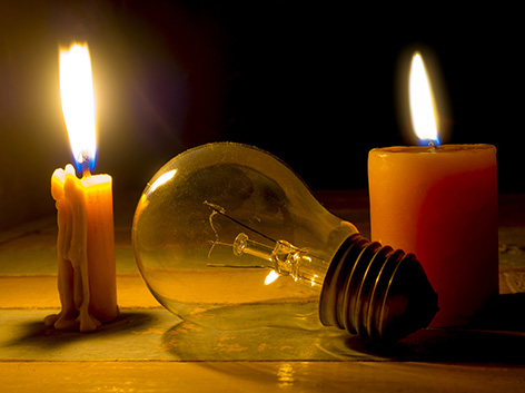 DMA Une ampoule éteinte placée entre deux bougies allumées